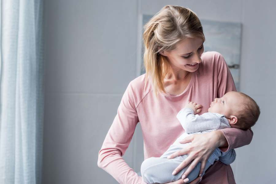 beautiful smiling mother holding infant in hands